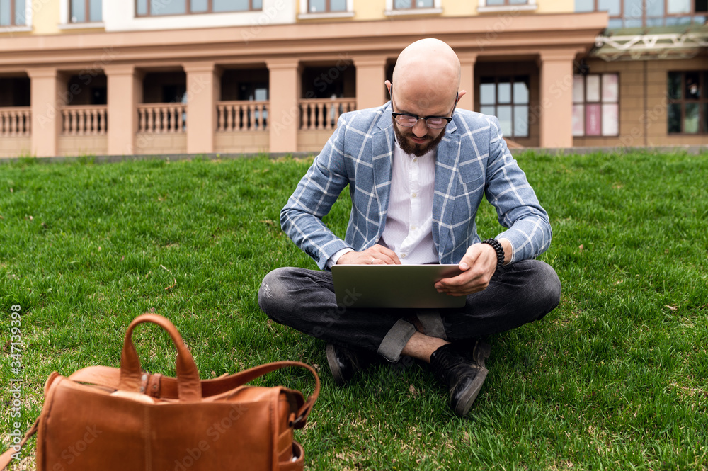 Young man using laptop outdoor. Freelance, student lifestyle, education, technology and online shopping concept