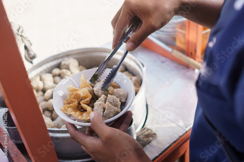 indonesian meatball street food vendor preparing the dish using tongs