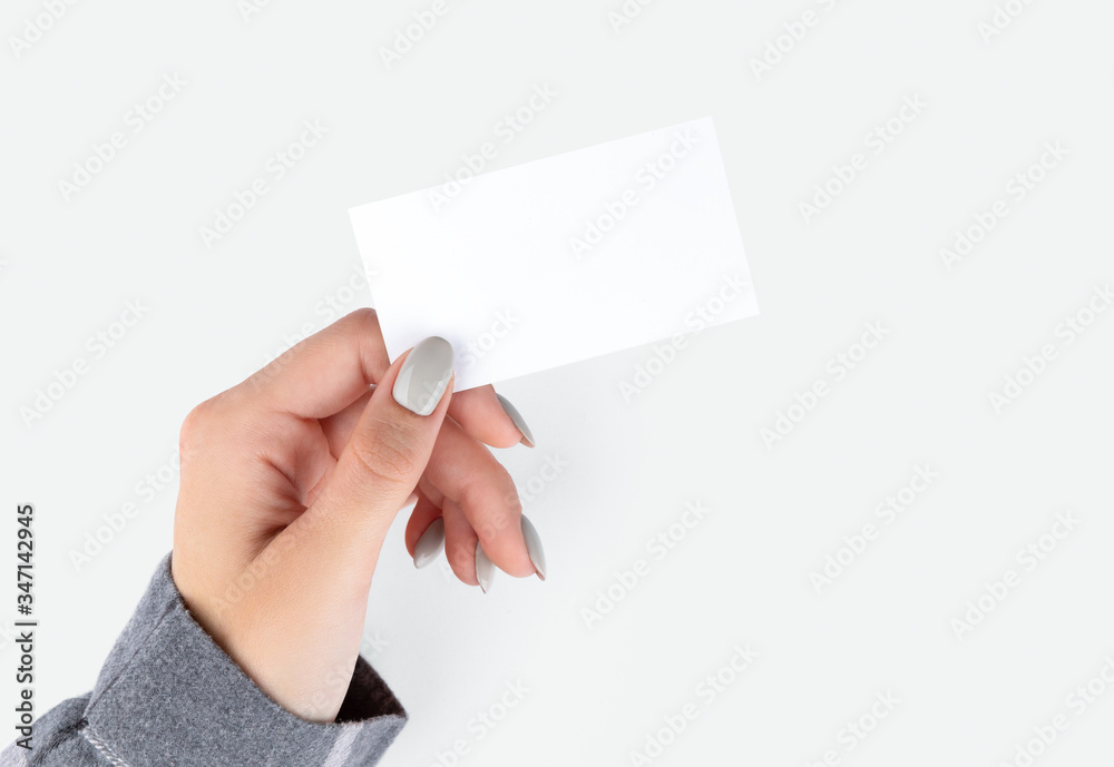 Fototapeta premium Beautiful womans hand with manicure holding business card