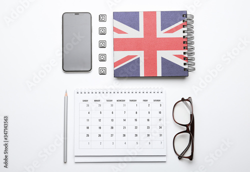 Calendar, notebook, glasses and mobile phone on white background, top view. Learning English photo