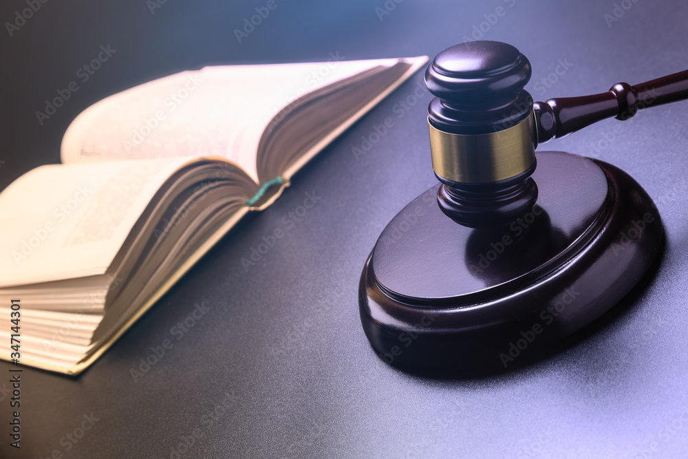 Judge's hammer close-up on a dark background. Open book. A symbol of justice. Legislation. Crime and punishment. Soft toning of the image. Judge's hammer close-up on a dark background. Open book. A symbol of justice. Legislation. Crime and punishment. Soft toning of the image.