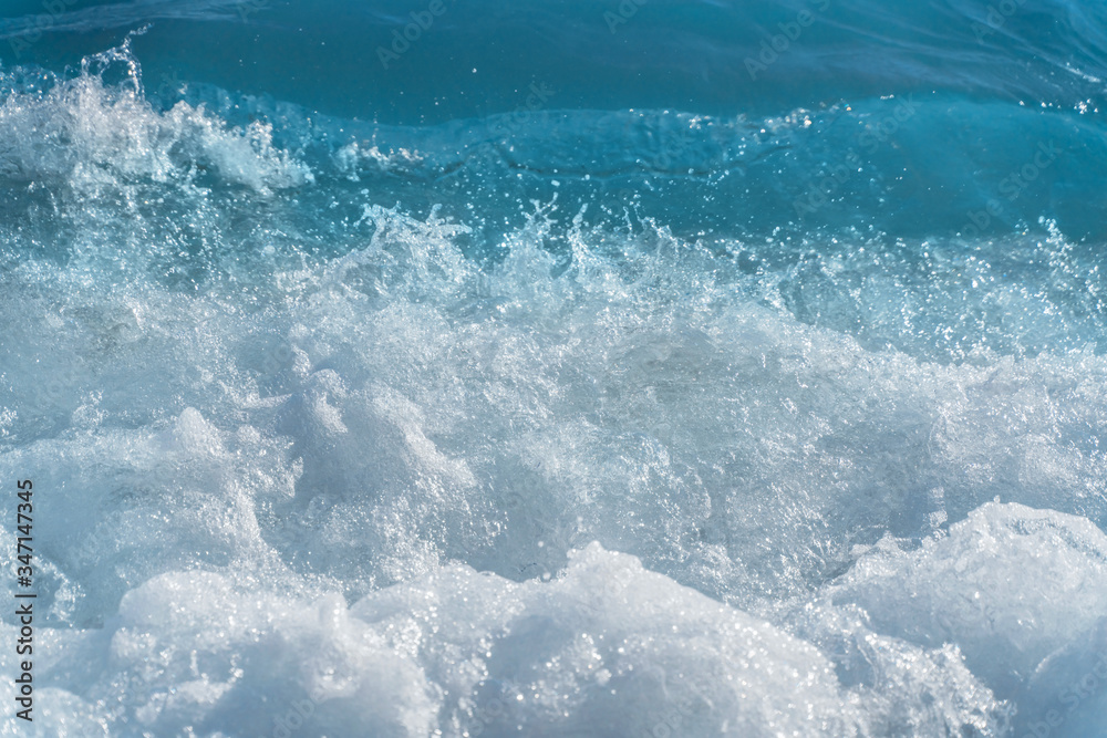 Texture Light blue surface of raging sea water with white foam and wave pattern.The azure surface of the ocean. Waves break at the shore. Natural background. Texture Light blue surface of raging sea water with white foam and wave pattern.The azure surface of the ocean. Waves break at the shore. Natural background.