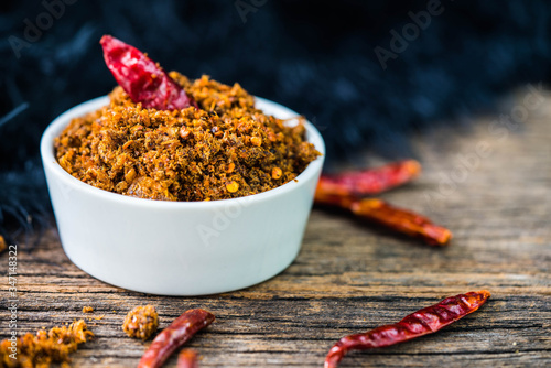 Spicy dried fishes chili paste with white ceramic container on wood background