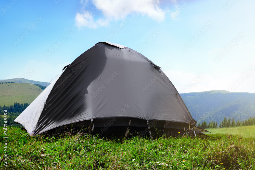 Grey camping tent in mountains on sunny day