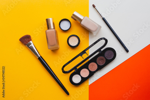 Creative flat lay of fashion bright nail polishes and decorative cosmetic on a yellow,orange and cream background. Minimal style. Copy space. Beauty blogger concept. Top view.