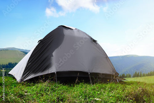 Grey camping tent in mountains on sunny day