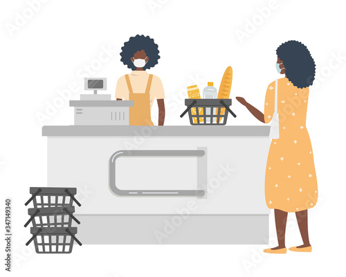 Supermarket cashier during coronovirus epidemic. Young black woman in a medical mask stands behind a cash register. Customer is also wearing a protective mask.There is a basket with products here.