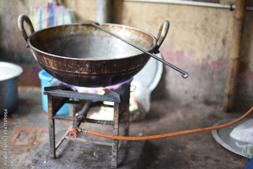 A large steel cooking pan on gas burner kept on a rooftop A large steel cooking pan on gas burner kept on a rooftop