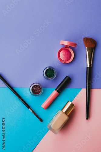 Creative flat lay of fashion bright nail polishes and decorative cosmetic on a blue, purple and pink background. Minimal style. Copy space. Beauty blogger concept. Top view.