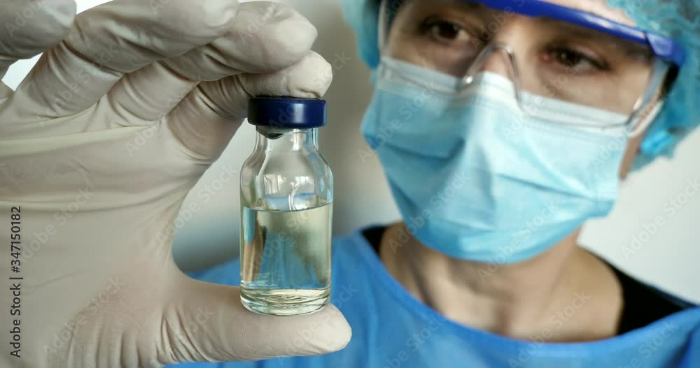 In the laboratory, a Caucasian female scientist in a medical mask analyzes an injection solution in vitro. pneumonia, conv2019, coronavirus, pandemic .. research, biochemistry, vaccination In the laboratory, a Caucasian female scientist in a medical mask analyzes an injection solution in vitro. pneumonia, conv2019, coronavirus, pandemic .. research, biochemistry, vaccination