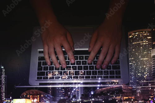 Double exposure of male programmer using laptop and cityscape, top view