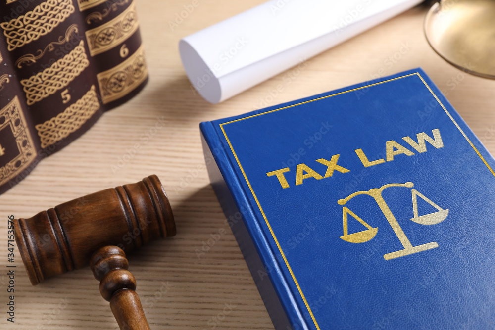 Tax law book and gavel on wooden table Tax law book and gavel on wooden table