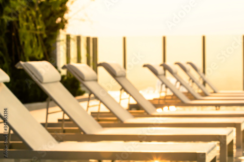 Blurred background of modern white beach chairs by a rooftop pool in calm evening