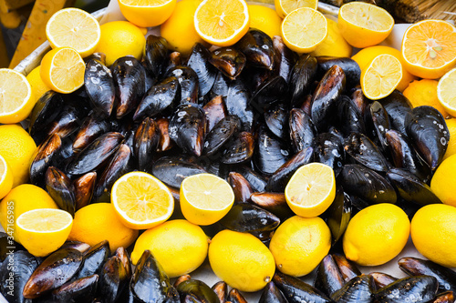 Boiled mussels in ceramic bowl garnished with fresh herbs and lemon. photo