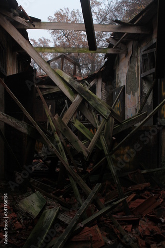 A room in an abandoned house in a park. The ceiling has collapsed and all the wooden beams are broken on the ground.