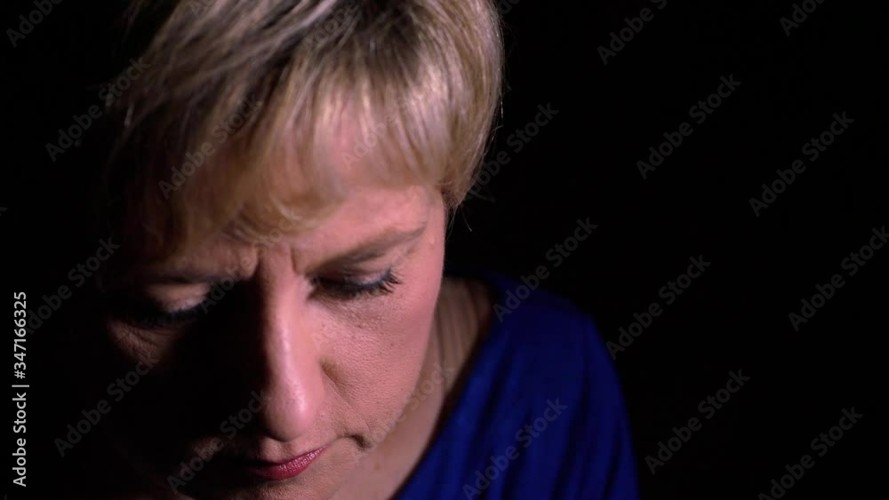 thoughtful mature woman raising her head and looking at camera thoughtful mature woman raising her head and looking at camera