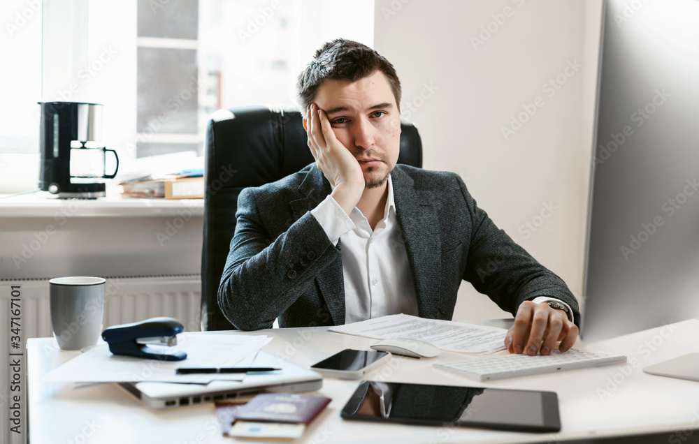 An overworked employee works on a desktop computer. Tired businessman or office worker falls asleep at the workplace. Sales manager, financial analyst or IT specialist, freelancer.