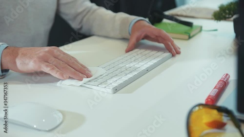 Close up handsman disinfecting computer keyboard with antiseptic spray and wet wipe s virus antibacterial pandemic sanitary infection clean coronavirus close up slow motion photo