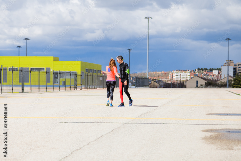 Young couple running on a road outside together Young couple running on a road outside together