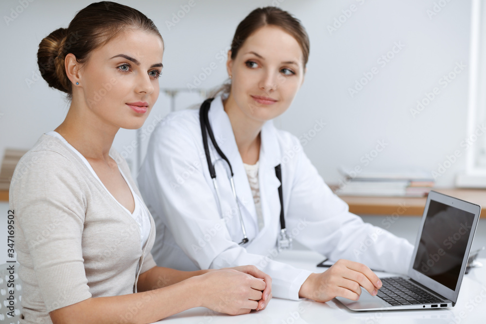 Doctor and patient are sitting and discussing health examination results while using laptop computer. Health care, medicine and good news concepts Doctor and patient are sitting and discussing health examination results while using laptop computer. Health care, medicine and good news concepts