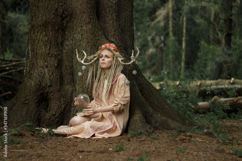 Charming girl in the image of a fairy in the forest thicket