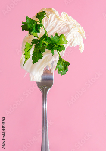  fresh lettuce , green parsley on a fork on a pink background,