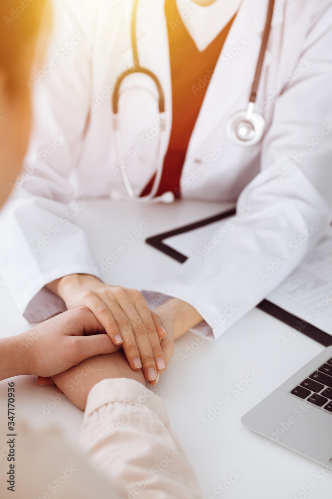 Hands of unknown woman-doctor reassuring her female patient in sunny room, close-up Hands of unknown woman-doctor reassuring her female patient in sunny room, close-up