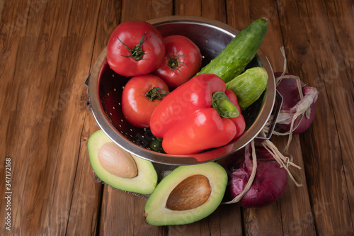 Fresh red tomatoes  bell pepper  cucumbers  red onions and avocado on a wooden background