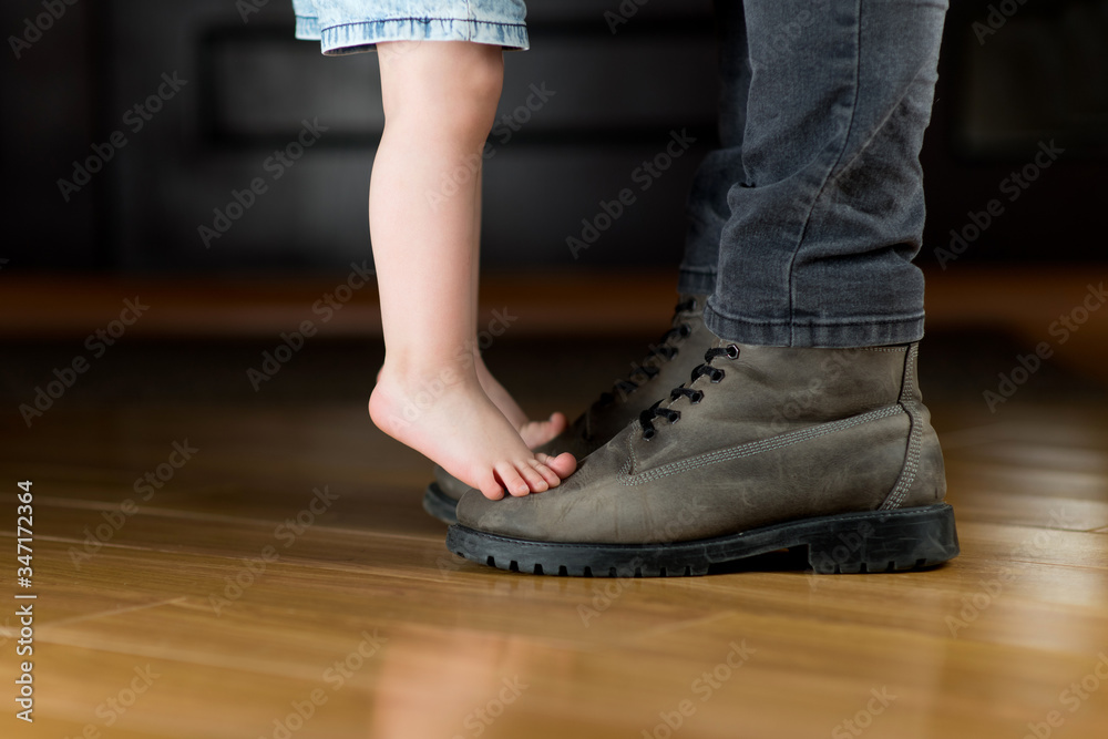 child meets or escorts his father to work. A girl stands on her father's boots child meets or escorts his father to work. A girl stands on her father's boots