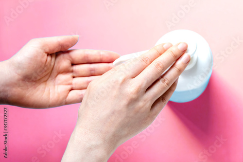 女性の手と消毒用ボトルとコピースペースとピンク色背景 女性が手を消毒するところ