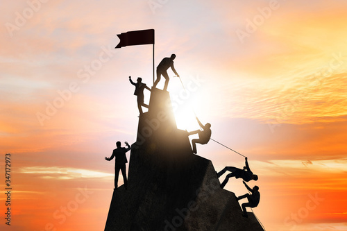 Concept of teamwork with team climbing mountain top
