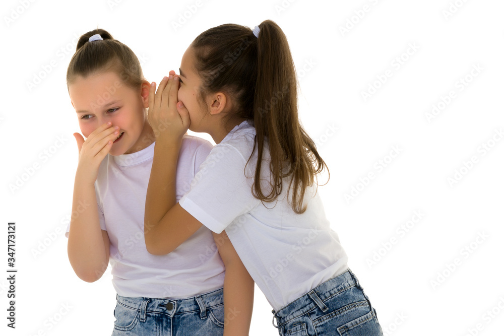Two cheerful little girls share secrets in each other s ear. Two cheerful little girls share secrets in each other s ear.