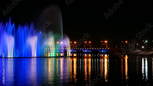Large floating light musical fountain on the night river. Bright colorful water show 