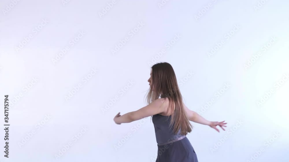 Medium long shot of young beautiful girl in a dress with long hair emotionally dancing contemporary, modern ballet dance in the studio in color back light, slow motion, isolated Medium long shot of young beautiful girl in a dress with long hair emotionally dancing contemporary, modern ballet dance in the studio in color back light, slow motion, isolated
