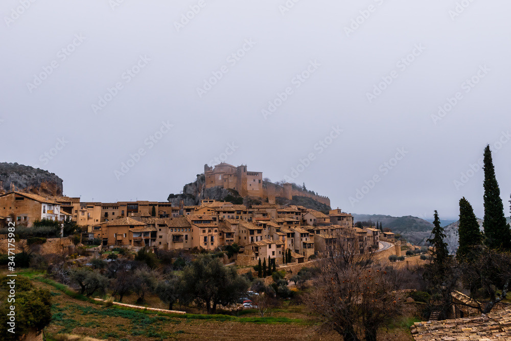 A picturesque panoramic view of the traditional buildings in the center of Alquézar (Huesca, Spain) on a hill covered by morning mist in winter