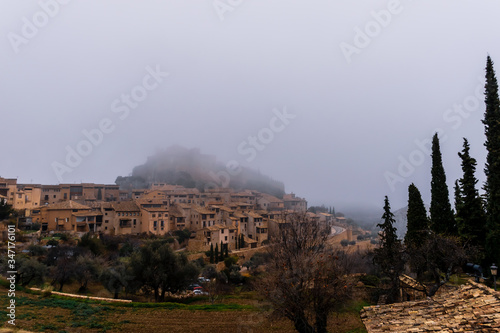 A picturesque panoramic view of the traditional buildings in the center of Alqu  zar  Huesca  Spain  on a hill covered by morning mist in winter