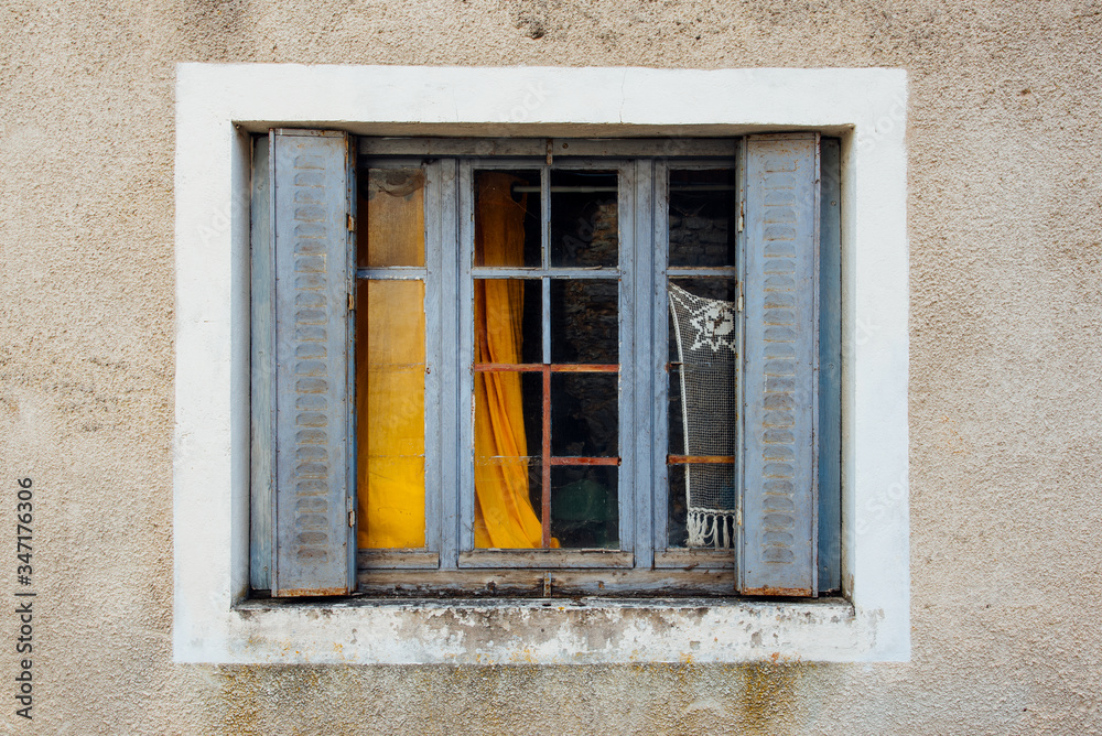 une vieille fenêtre aux rideaux métalliques bleus et un vieux rideau jaune dans une maison abandonnée une vieille fenêtre aux rideaux métalliques bleus et un vieux rideau jaune dans une maison abandonnée
