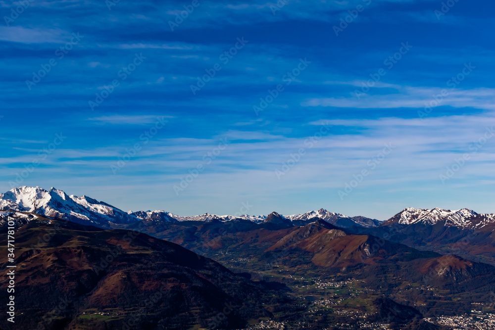 A picturesque landscape view of the snow capped French Pyrenees mountain range in the afternoon under the blue sky in winter