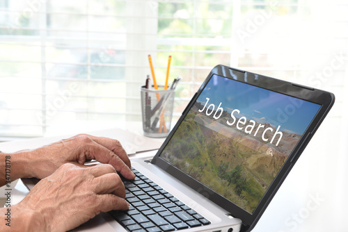 Online Job Search Concept. Closeup of a man sitting at his laptop computer visiting a web site with search box.