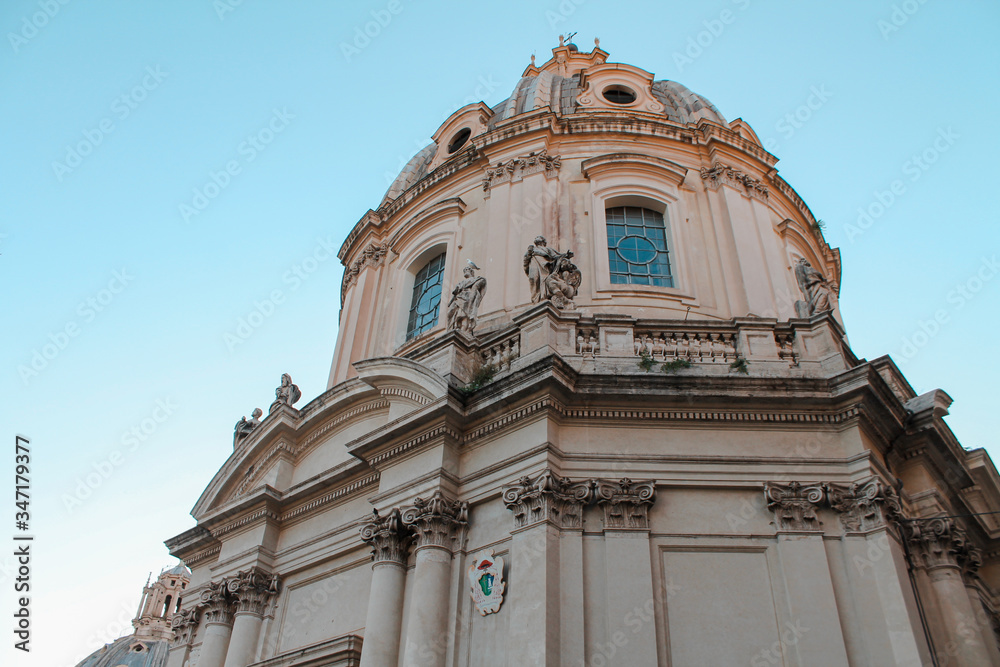 white church, temple in Rome (Italy) with statues on the facade against the blue sky