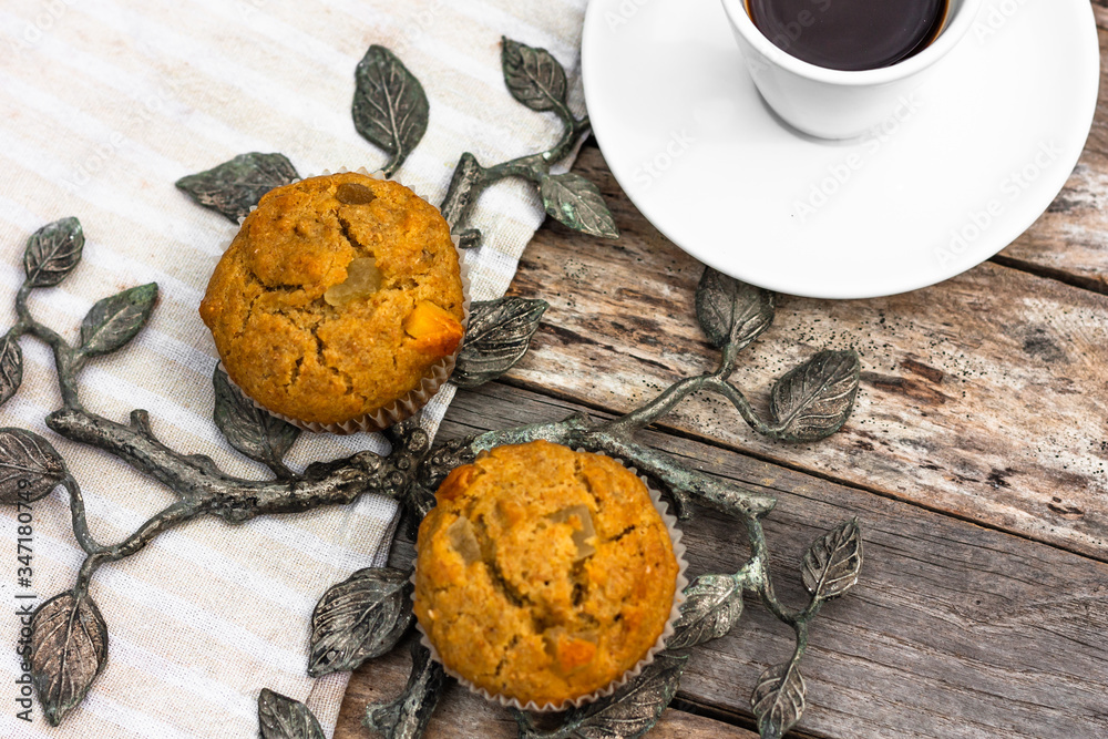 Fototapeta premium Fresh banana muffins and cup of coffee espresso on wooden table with wrought iron elements. Top view. Morning breakfast concept