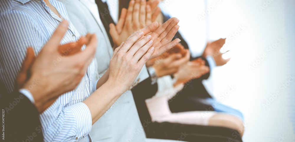 Business people clapping and applause at meeting or conference, close-up of hands. Group of unknown businessmen and women in modern white office. Success teamwork or corporate coaching concept