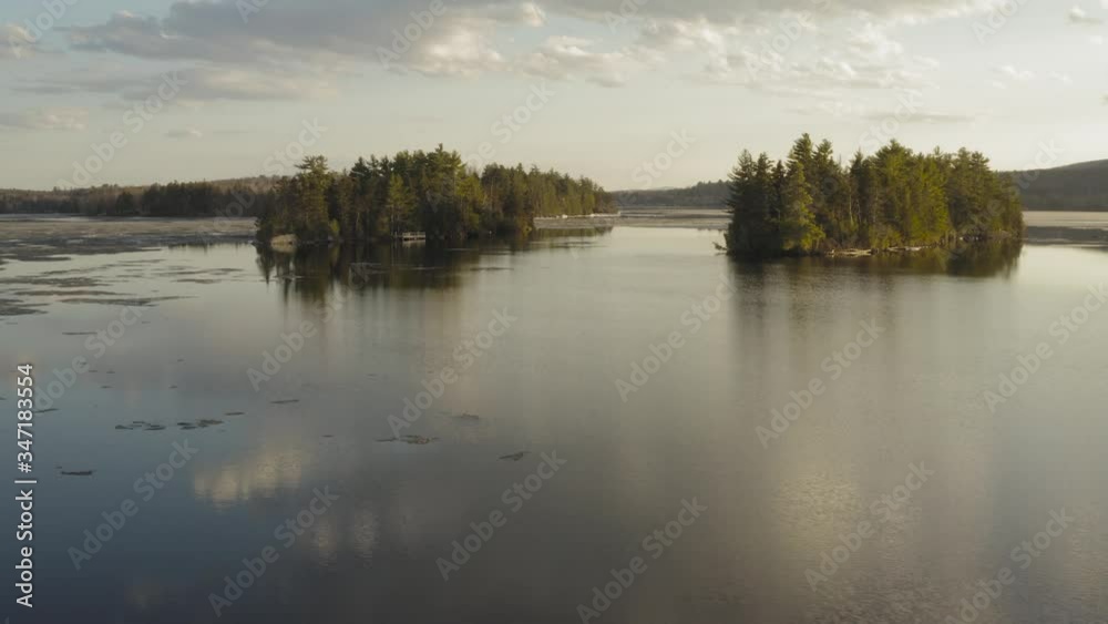 Two islands surrounded by calm water and ice during a spring sunset AERIAL Two islands surrounded by calm water and ice during a spring sunset AERIAL