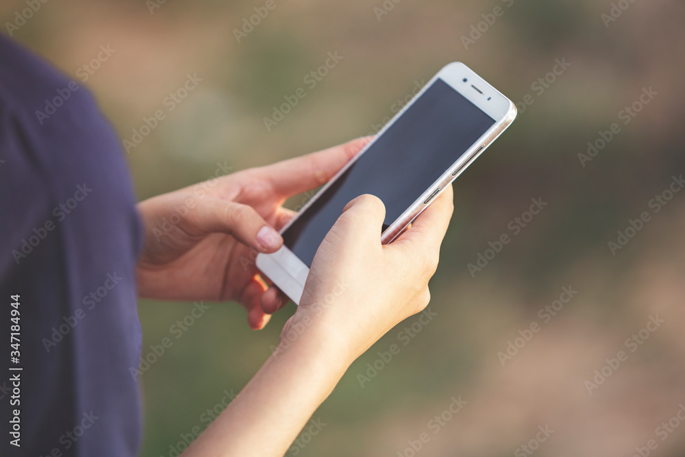 Woman hand using a smartphone, outdoor, close up