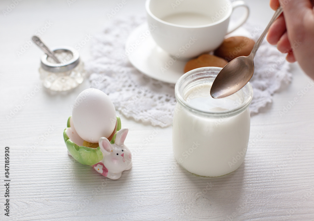 Healthy breakfast served on white dresser scarf with hand holding silver spoon