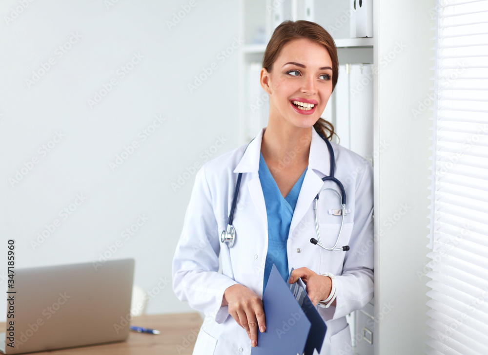 Smiling female doctor with a folder in uniform standing at hospital Smiling female doctor with a folder in uniform standing at hospital