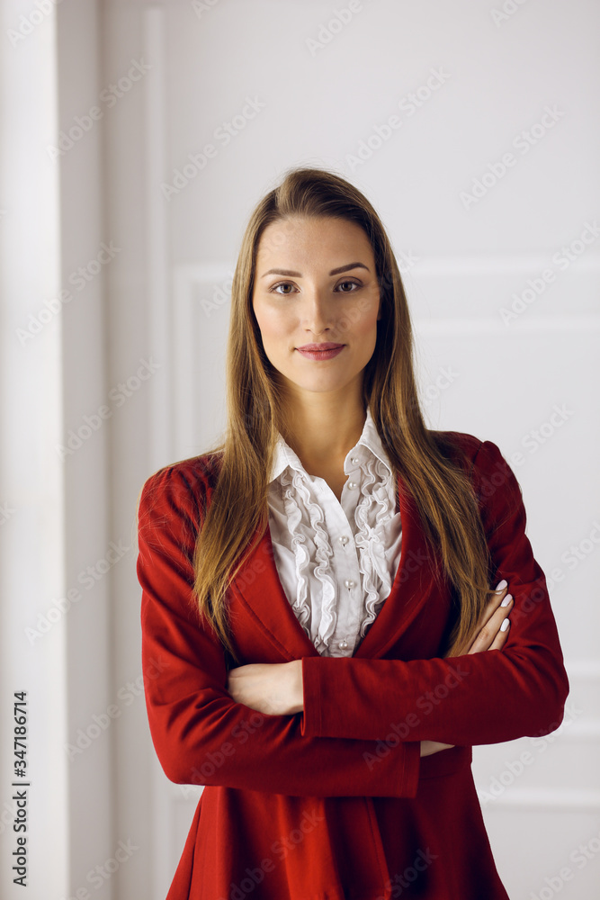 Business woman in red standing at modern office. Headshot of a young female entrepreneur Business woman in red standing at modern office. Headshot of a young female entrepreneur