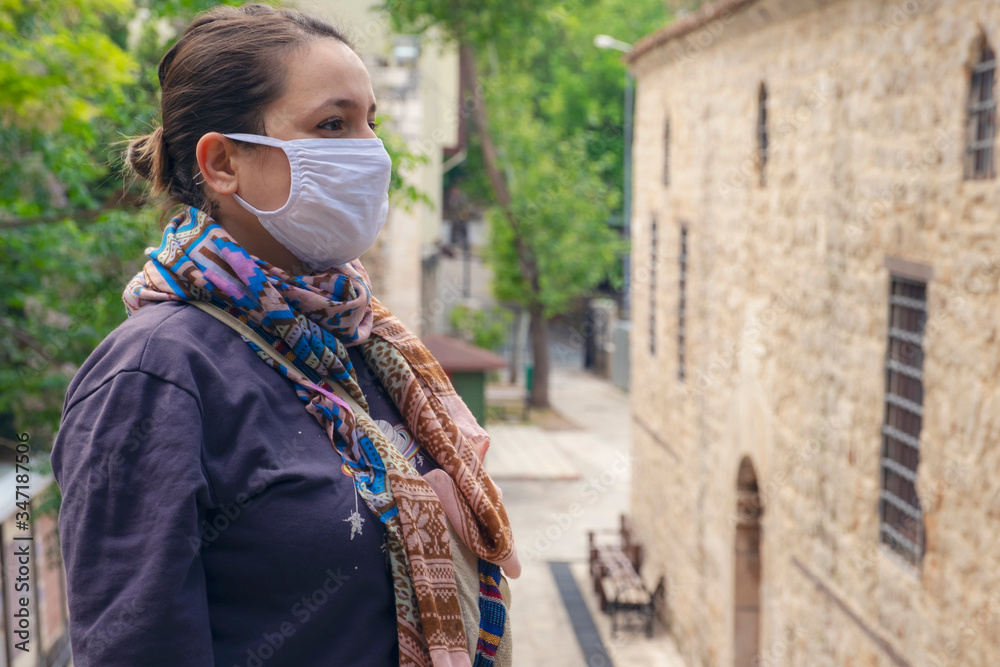Obraz premium Young adult woman standing look at the camera with mask during corona (covid19) outbreak in the street. 
