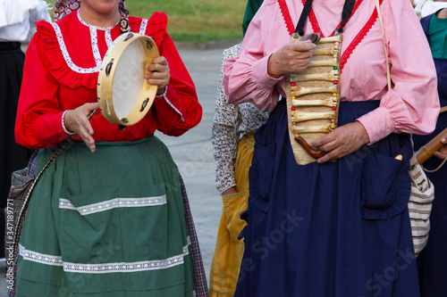 Anonymous women in local costumes playing tambourine and handmade bones instrument. Traditional music festival with people performing on street in Las Palmas, Gran Canaria island