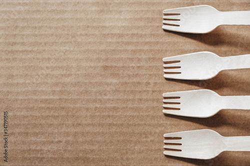 Wooden forks on a cardboard background. Eco friendly disposable tableware. Top view. Copy, empty space for text photo